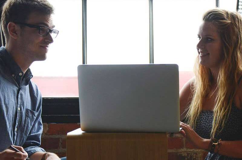 Male and female professionals talking near a laptop